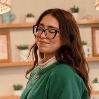 A woman wearing glasses and a sweater in a kitchen.