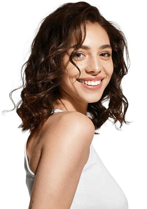 A young woman with wavy brown hair and light skin smiles at the camera, wearing a white sleeveless top against a plain background.