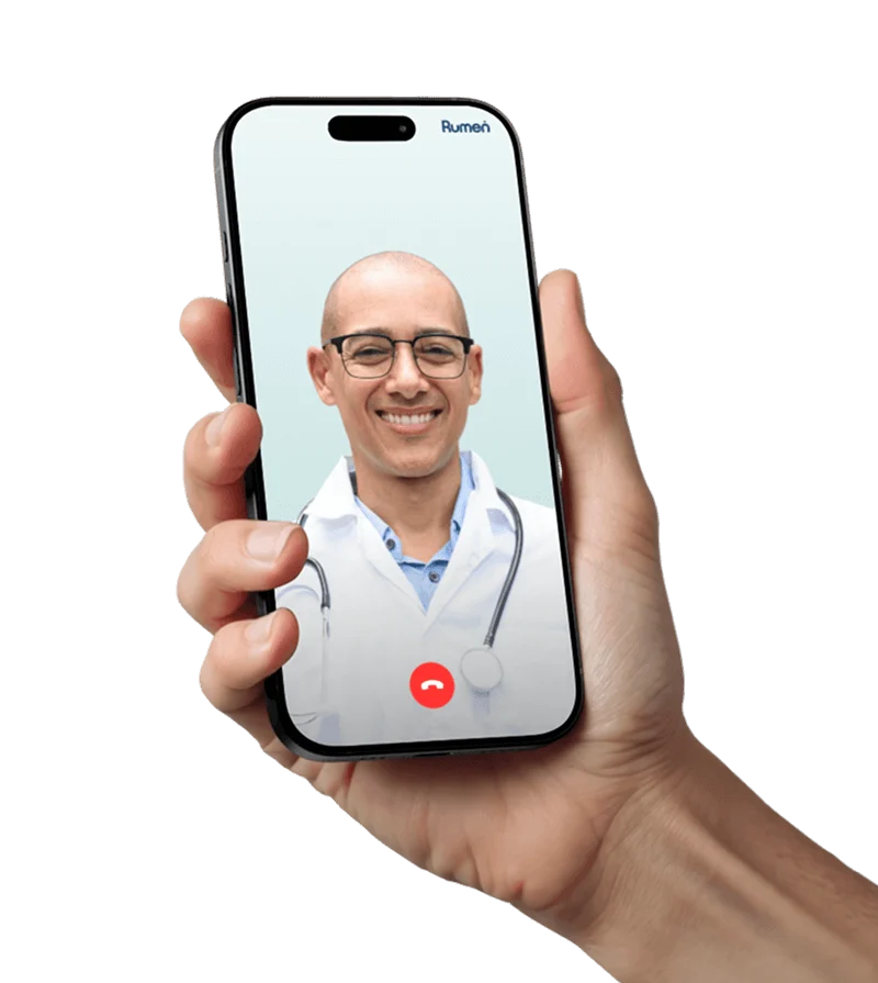 A hand holding a smartphone displaying a video call with a smiling male doctor wearing glasses and a stethoscope.