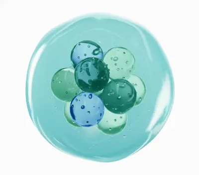 A cluster of blue and green glass-like spheres is encased in a transparent, circular gel on a white background.