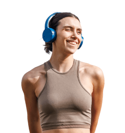 Woman wearing a sleeveless taupe crop top and blue headphones, smiling and looking to the side against a plain background.