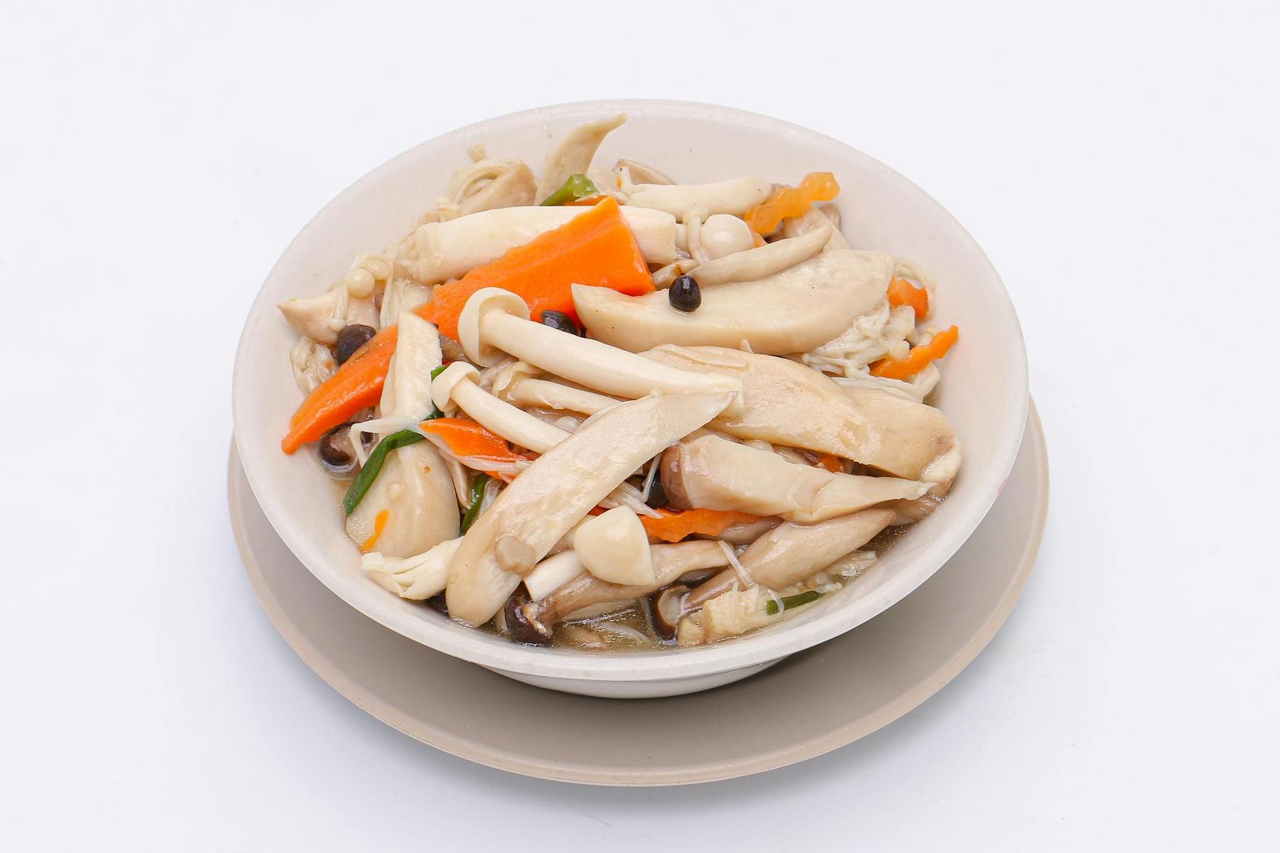 A white bowl of mixed mushrooms and sliced carrots in a light broth, placed on a matching plate against a plain white background.