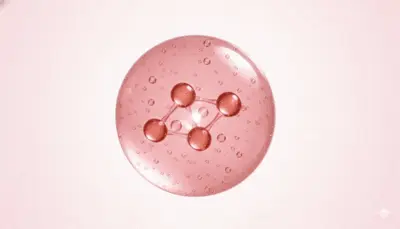 A close-up view of a pink translucent button with four holes and small water droplets on its surface, set against a light pink background.